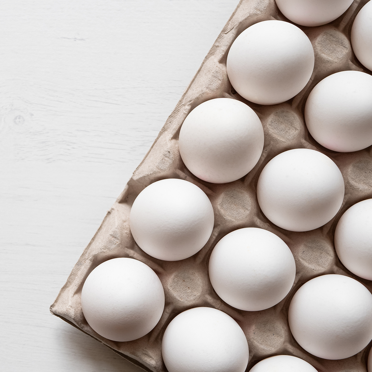 Detail of white chicken eggs in paper tray.
